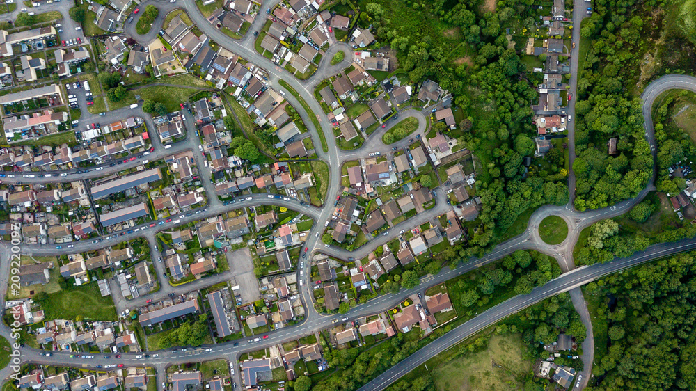 Wall mural top down aerial view of an urban area in a small town surrounded by trees and greenery