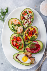 various stuffed avocadoes on  white plate