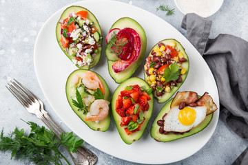 various stuffed avocadoes on  white plate