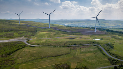 Aerial view of large wind turbines on a rural hillside in Wales