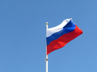 Waving Russian flag isolated on the background of clear blue sky