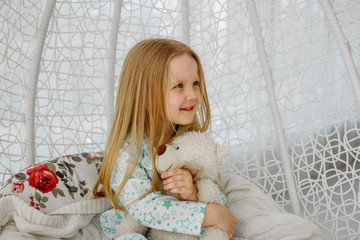 Little girl sitting in a chair suspended cocoon or in a rocking chair in a bright interior. little girl sitting in chair cocoon.