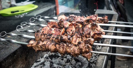 Barbeque kebab grilling on the fire outside. Meat on metal skewers on the flame