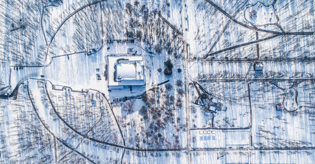 Fototapeta premium Top view of central city park during winter with snow. Aerial view of winter urban park with no people