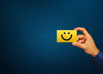 Hand of client show a feedback with smiley face card. Service rating, satisfaction concept