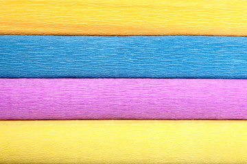 Texture of four different-colored rolls of wrinkled paper.