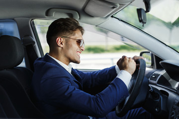 Happy businessman sits shows his emotions sitting at the steering wheel inside the car