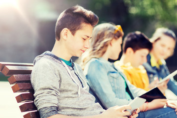 technology, internet and people concept - happy teenage boy with tablet pc computer outdoors