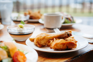 Crispy deep fried chicken drum legs and salad on dinner table, close up