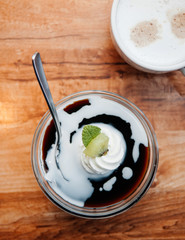 Creamy vanilla caramel pudding with Kiwi in glass cup and coffee on wood table, top view