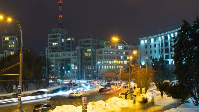 Kharkiv, Ukraine. Freedom square with car traffic and the Derzhprom or Gosprom building is a constructivist structure. Time-lapse at night with people silhouettes and dark sky