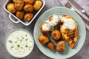Grilled chicken fillet with baked potatoes and garlic yogurt dip.