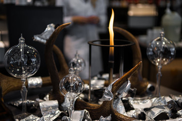 selective focus of fire, flasks and foil on table and female scientist on blurred background