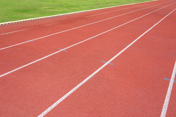 White lines of stadium and texture of running racetrack red rubber racetracks in outdoor stadium are 8 track and green grass field,empty athletics stadium with track.