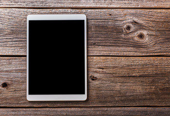 White tablet pc on old wood table background.