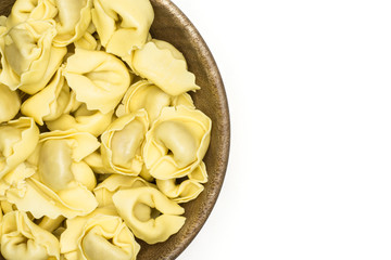 Raw tortellini pasta in a wooden bowl flatlay isolated on white background Italian traditional dumpling.