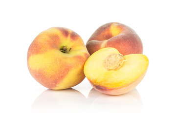 Two ripe yellow peaches and one sliced half with a drupe isolated on white background.