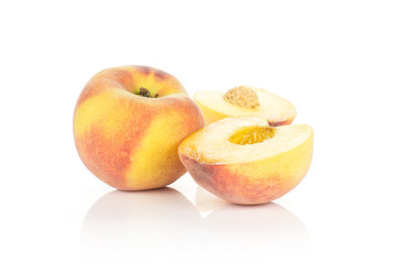 One ripe yellow peach and two halves isolated on white background.