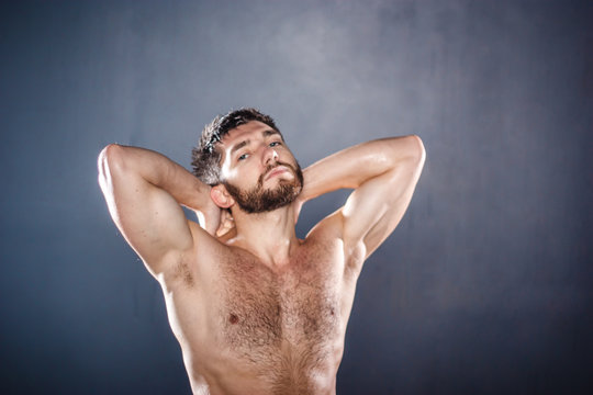 Portrait of shirtless handsome sensual fit young man with naked torso, hands lifted (selective focus)