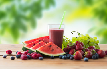 healthy eating, food, dieting and vegetarian concept - glass with fruit and berry juice or smoothie on wooden table over green natural background