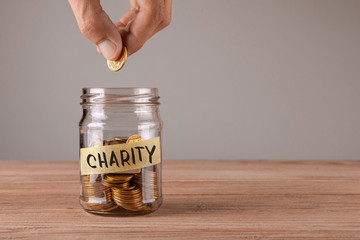 Charity. Glass jar with coins and an inscription charity. Man holds  coin