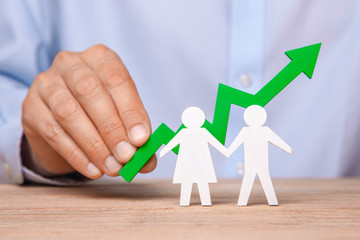 Fototapeta na wymiar Growth of the family budget. Man holds green arrow up against pair of man and woman