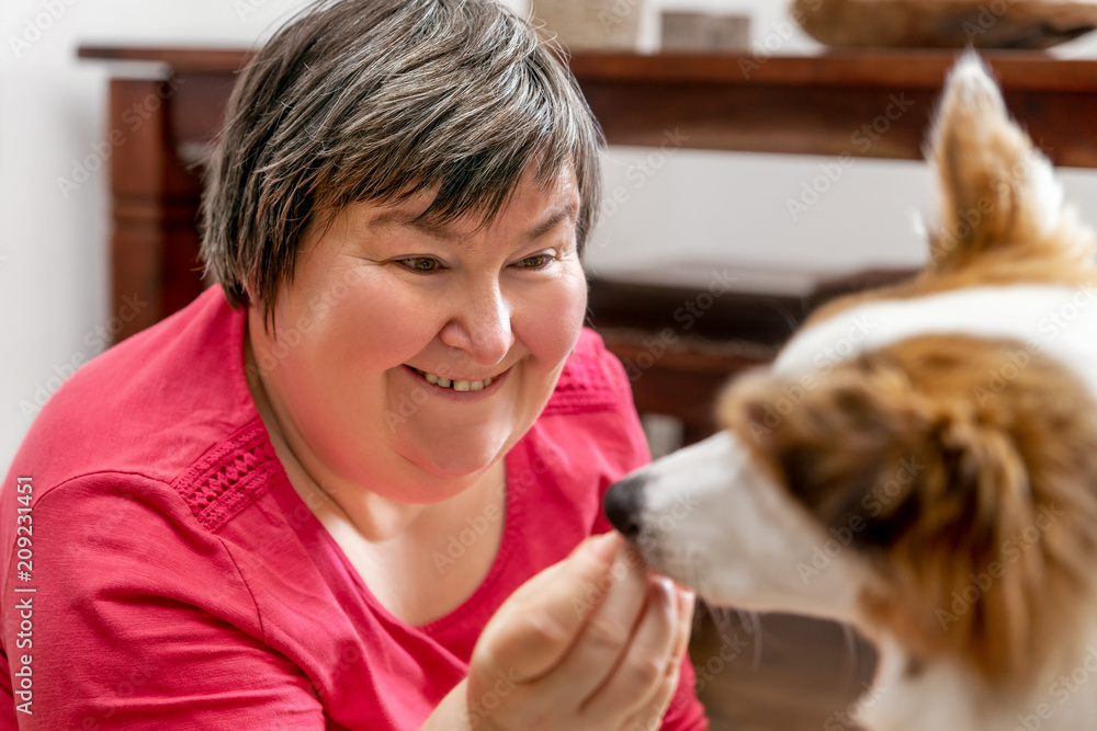 Wall mural Geistig behinderte Frau gibt Hund ein Leckerli, Konzept tiergestütze Therapie