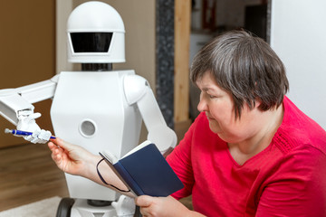 Roboter bringt einen Stift, geistig behinderte Frau mit Buch daneben - obrazy, fototapety, plakaty