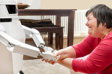 Geistig behinderte Frau spielt mit einem Roboter, Konzept Betreuung und Freundschaft - obrazy, fototapety, plakaty