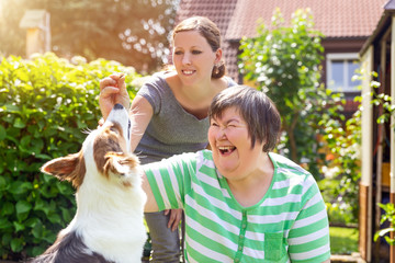 Alternativetherapie mit einem Hund, geistig behinderte Frau und Therapeutin im Garten - obrazy, fototapety, plakaty