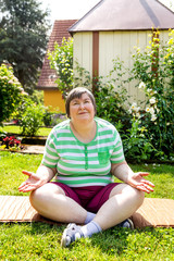 Geistig behinderte Frau sitzt im Garten, Konzept Yoga für Entspannung und Körpergefühl