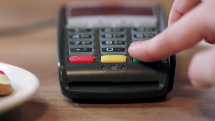 Pos terminal payment in cafe. Woman hand enter pin code on payment terminal. Banking services of electronic money. Credit card machine for money transaction. Closeup of female hand using bank terminal