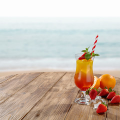 Summer drink in big glass and orange and red color. Fresh fruits decoration. 