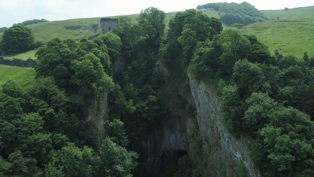 4K Aerial shot over secret cave surrounded by trees.