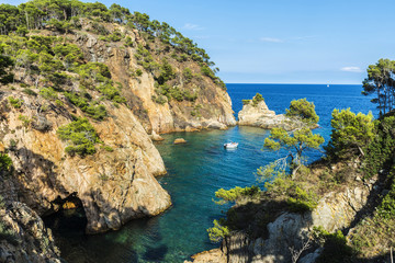 Yacht next to cliff in the Costa Brava, Catalonia, Spain