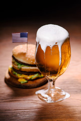 tasty burger with glass of beer on wooden table