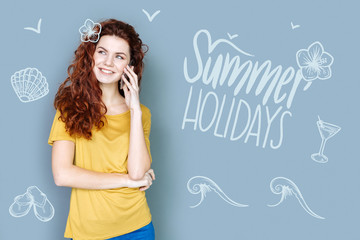 Summer at the seaside. Emotional young woman feeling happy and describing her wonderful summer holidays while talking on the phone with her friend