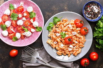 Pasta and salad with mozzarella and cherry tomatoes. View from above. Italian dish