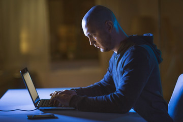 cybercrime, hacking and technology crime - male hacker in dark room using laptop computer for cyber...