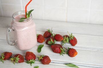 Healthy strawberry smoothie with scattered ripe berries on the table