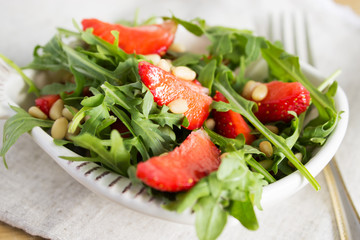 Salad of arugula and strawberries with pine nuts.