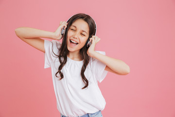 Happy teen girl 8-10 in casual clothing singing with closed eyes while listening to music via...