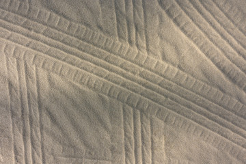Many lines texture of the car wheel footprint with shadow of pine branch on sand beach