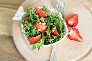 Salad of arugula and strawberries with pine nuts. Top view.