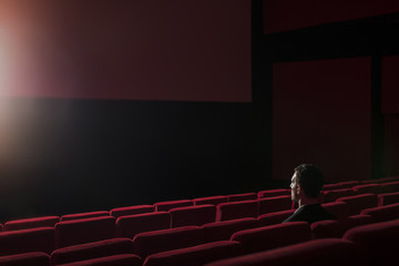 portrait of handsome young man alone at the cinema, sitting alone at the cinema