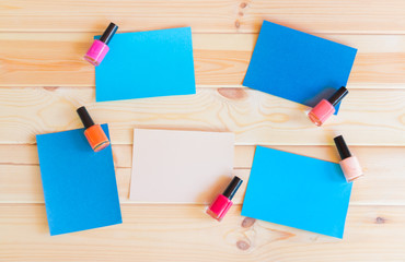 Paper cards and nail polishes on wooden background