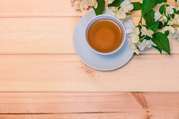 Green tea and jasmine flowers on wooden background. Top view, copy space.