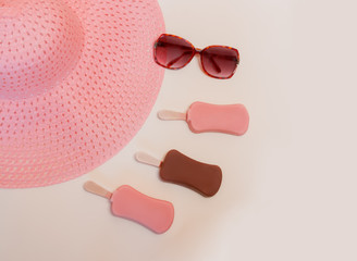 Ice cream on sticks, sunglasses and summer hat on pastel colored background. Summer creative concept.