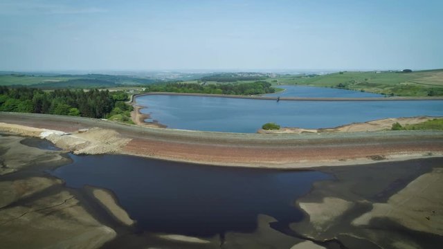 4K aerial drone shot of dried up reservoir on sunny day.