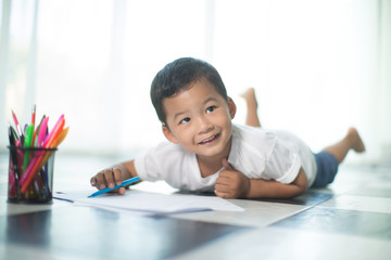 Naklejka premium happy Asia little boy writing something in paper,flare light